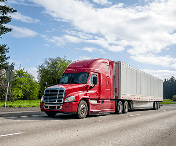 Red semi truck driving down a freeway